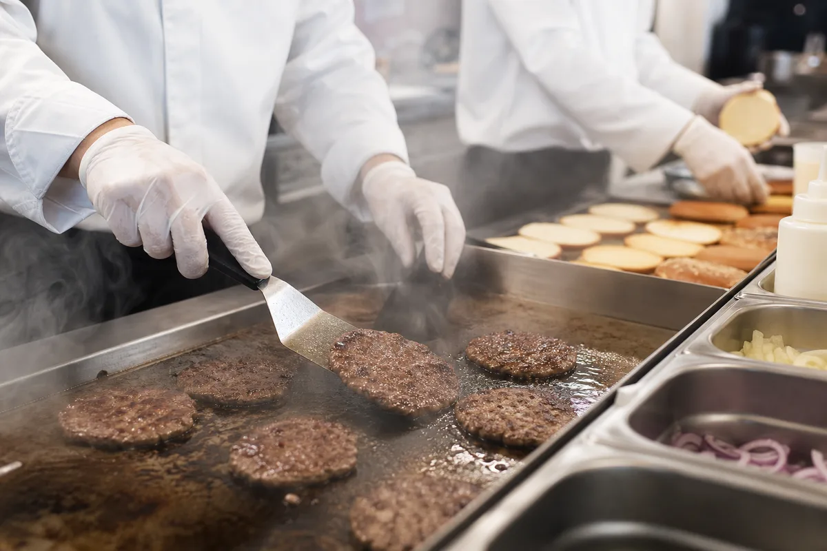 Équipe de cuisine préparant des burgers sur une ligne de production en restauration rapide